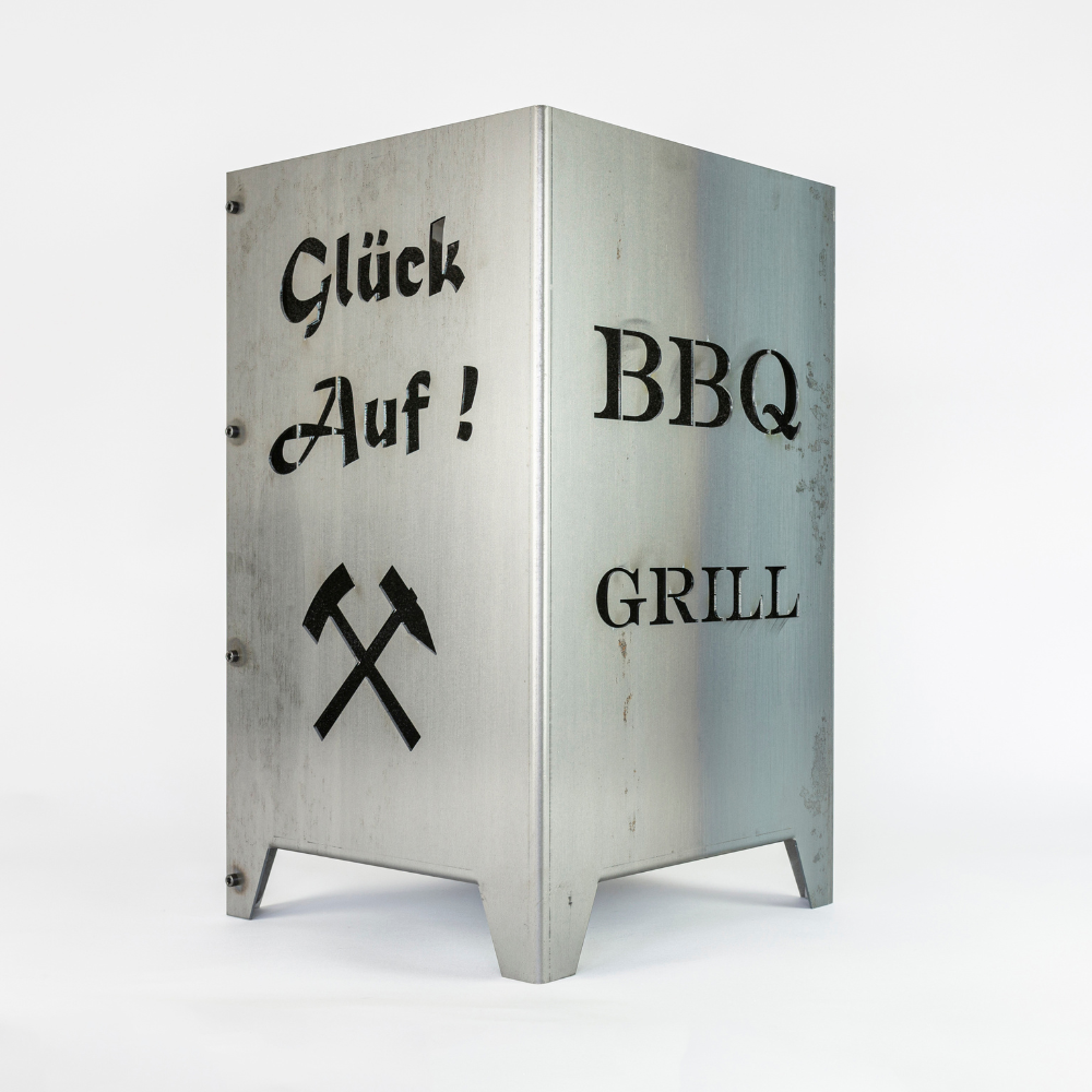 Feuersäule aus Stahl gefertigt mit Schriftzug BBQ Grill und Schriftzug Glück auf. Symbol Schlägel und Eisen unter dem Schriftzug Glück auf.